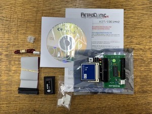 A RetroClinic kit still in its packaging: a CompactFlash IDE interface board, a grey ribbon cable, a CD and an instruction sheet labelled KIT/IDE1MHZ